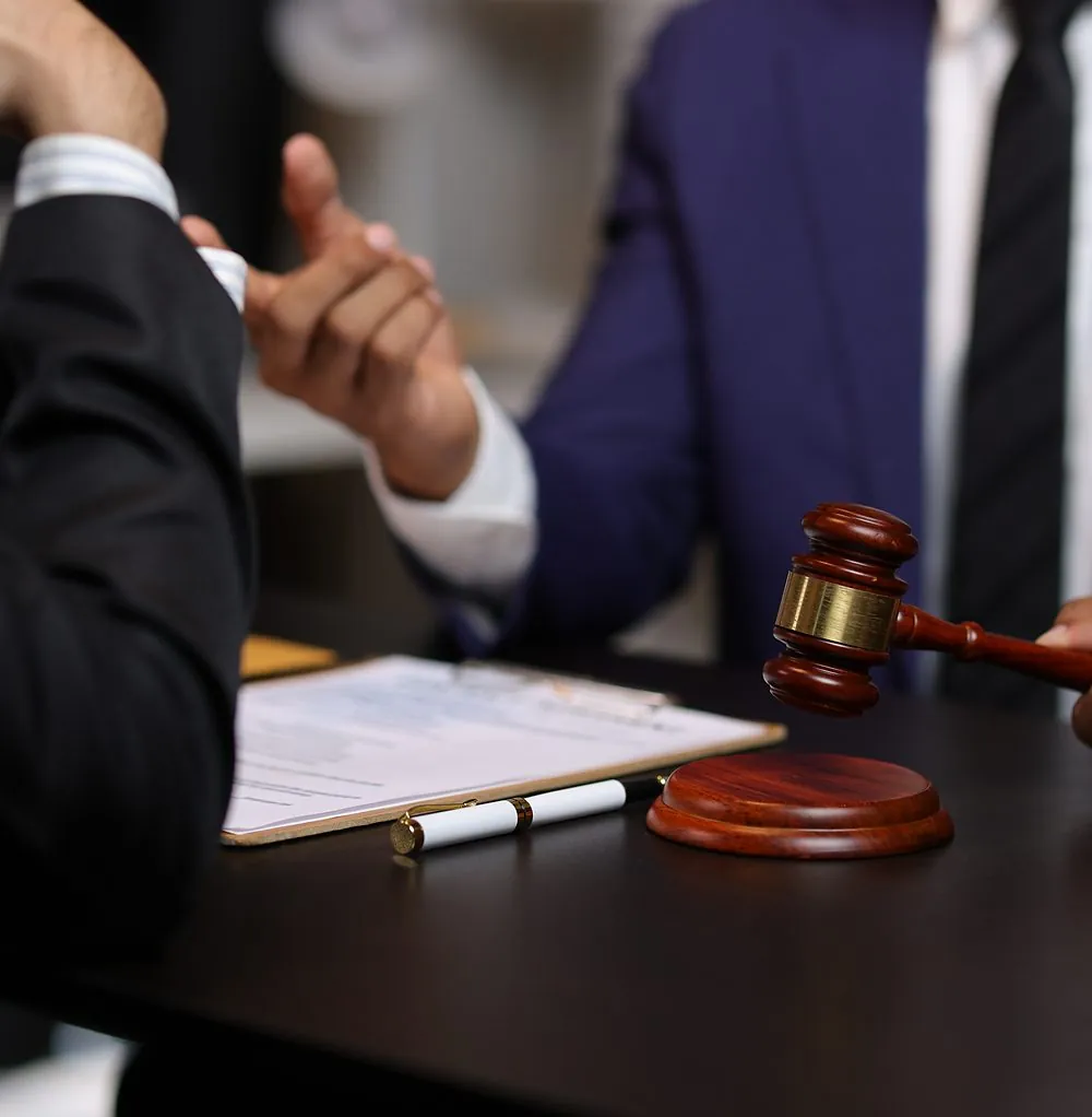Two people discussing papers across a desk with a gavel