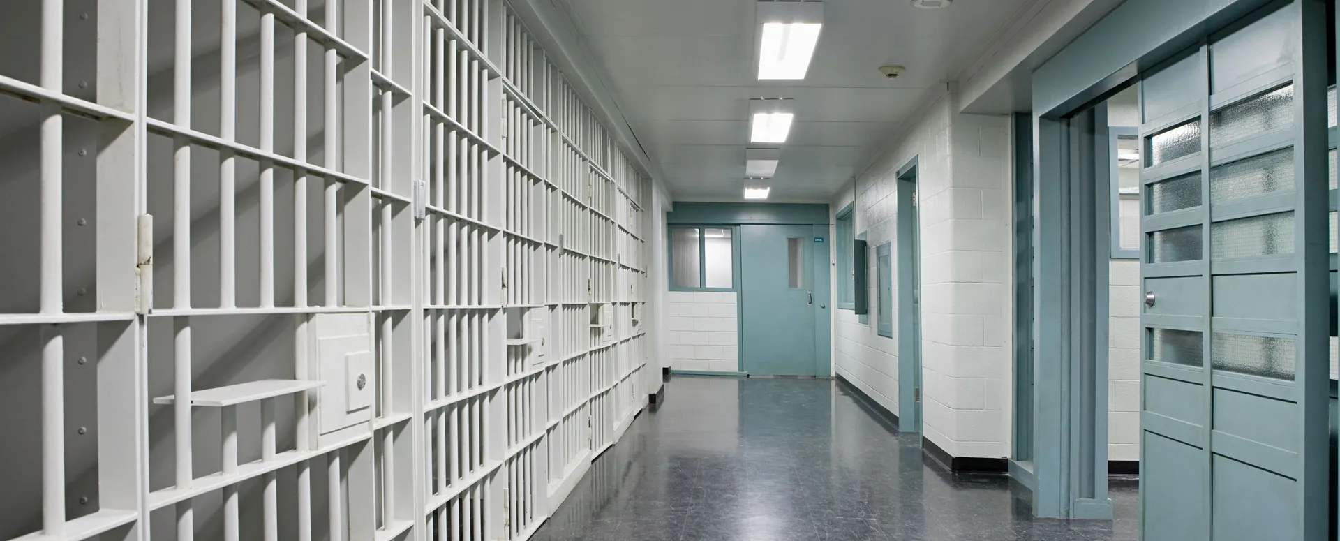 An empty jail corridor lined with cells